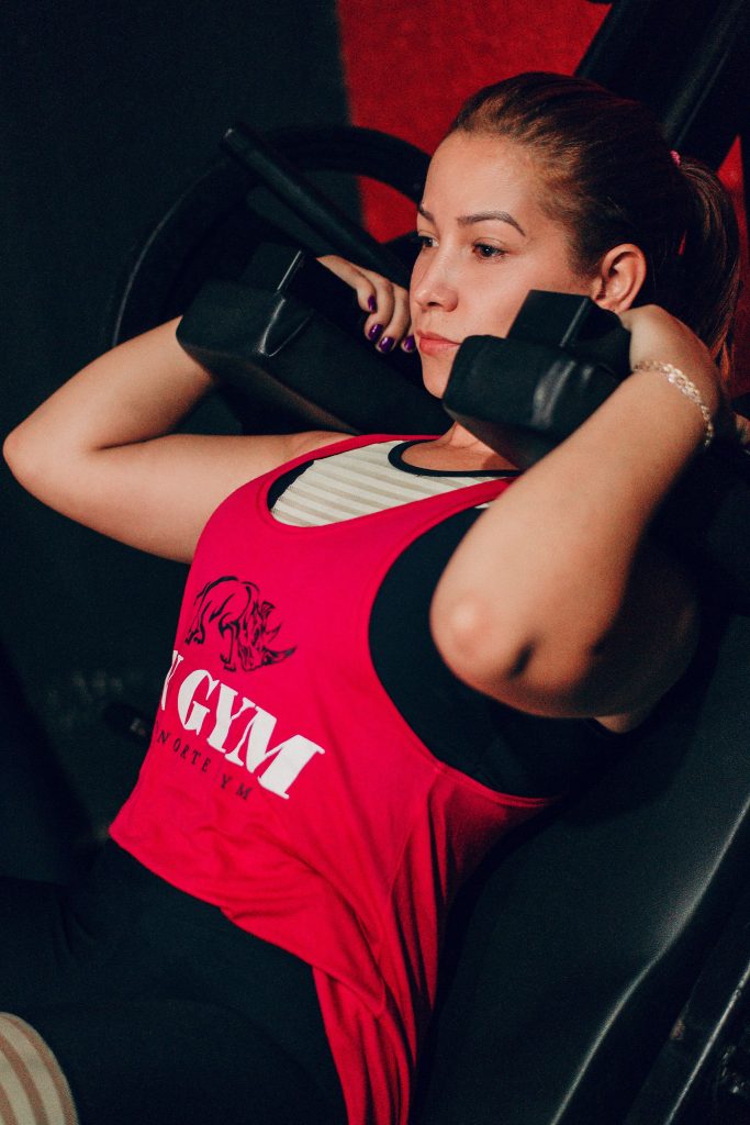Focused woman lifting dumbbells in gym for strength training.
